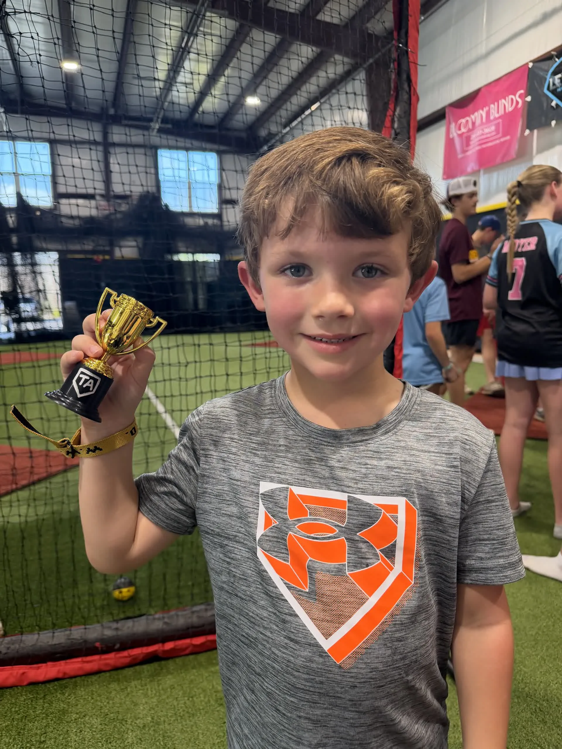Young boy proudly holding a trophy at his birthday party at Taylor'd Athletics