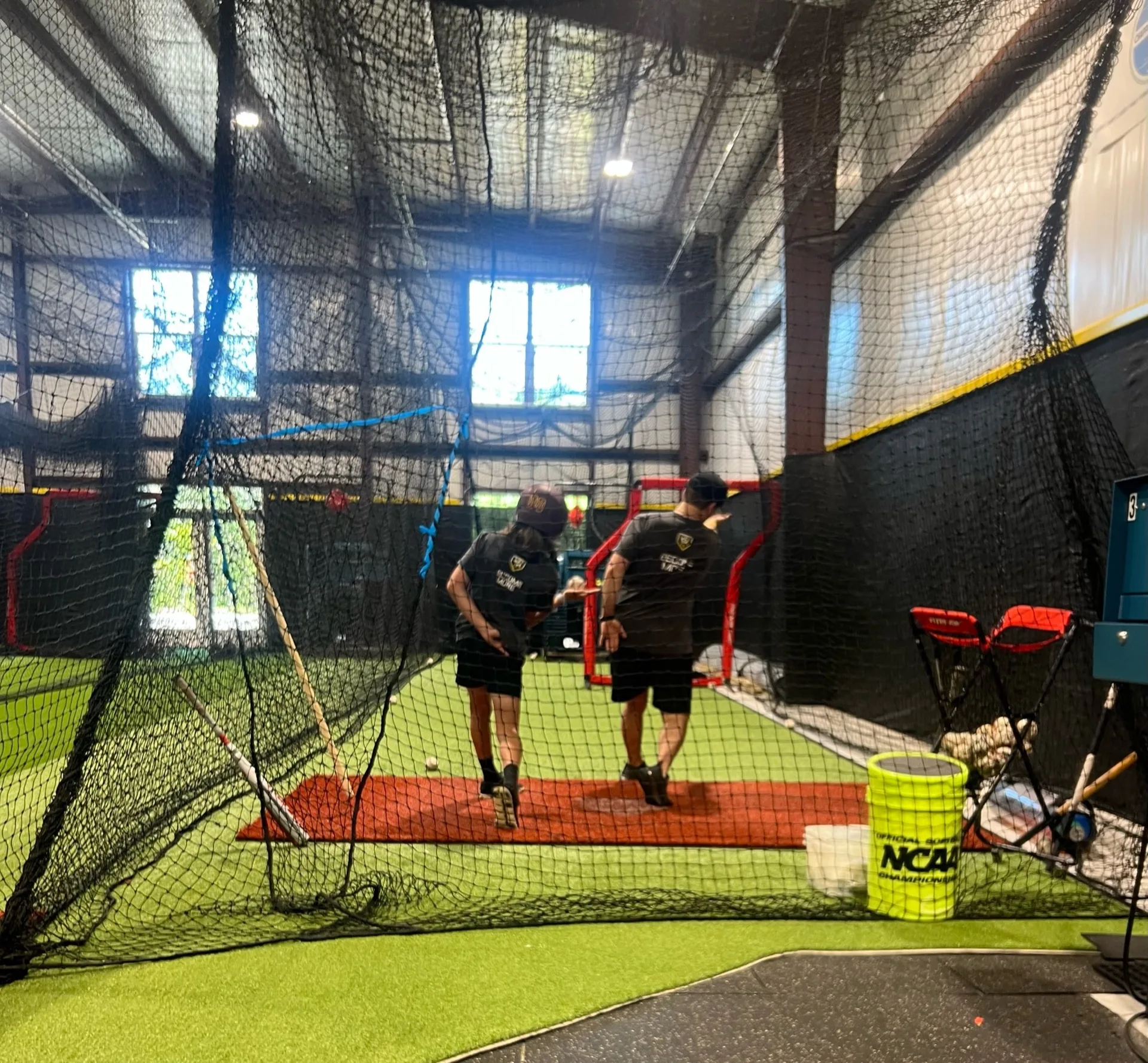 Two Taylor'd Athletics coaches working together inside the batting cage
