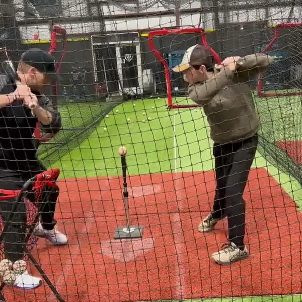 Coach instructing a young player at the batting tee