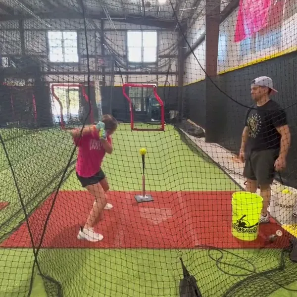 Female athlete hitting the tee with coach watching