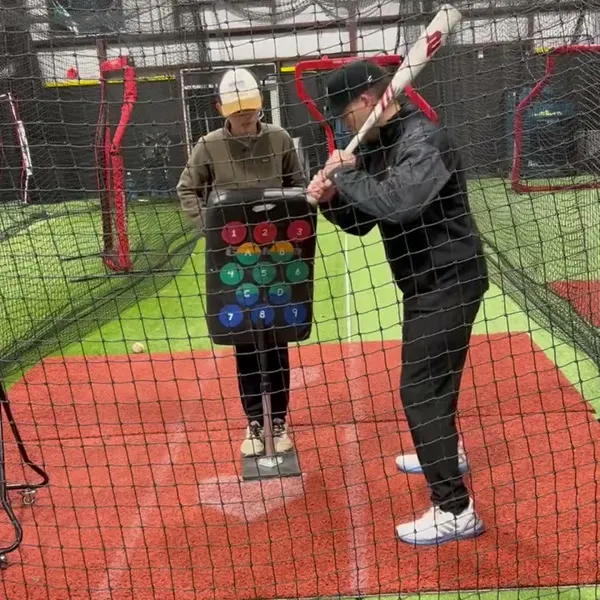 Player hitting off a colored-ball pitching machine