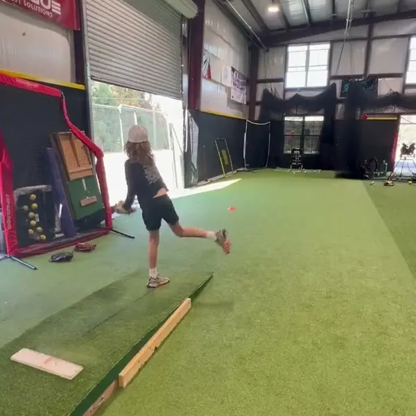 Player pitching from the mound in the open facility