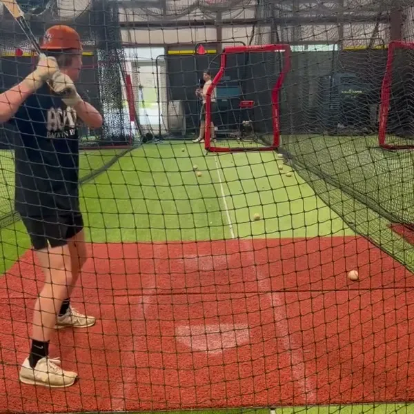 Teen athlete taking a full swing in the batting cage