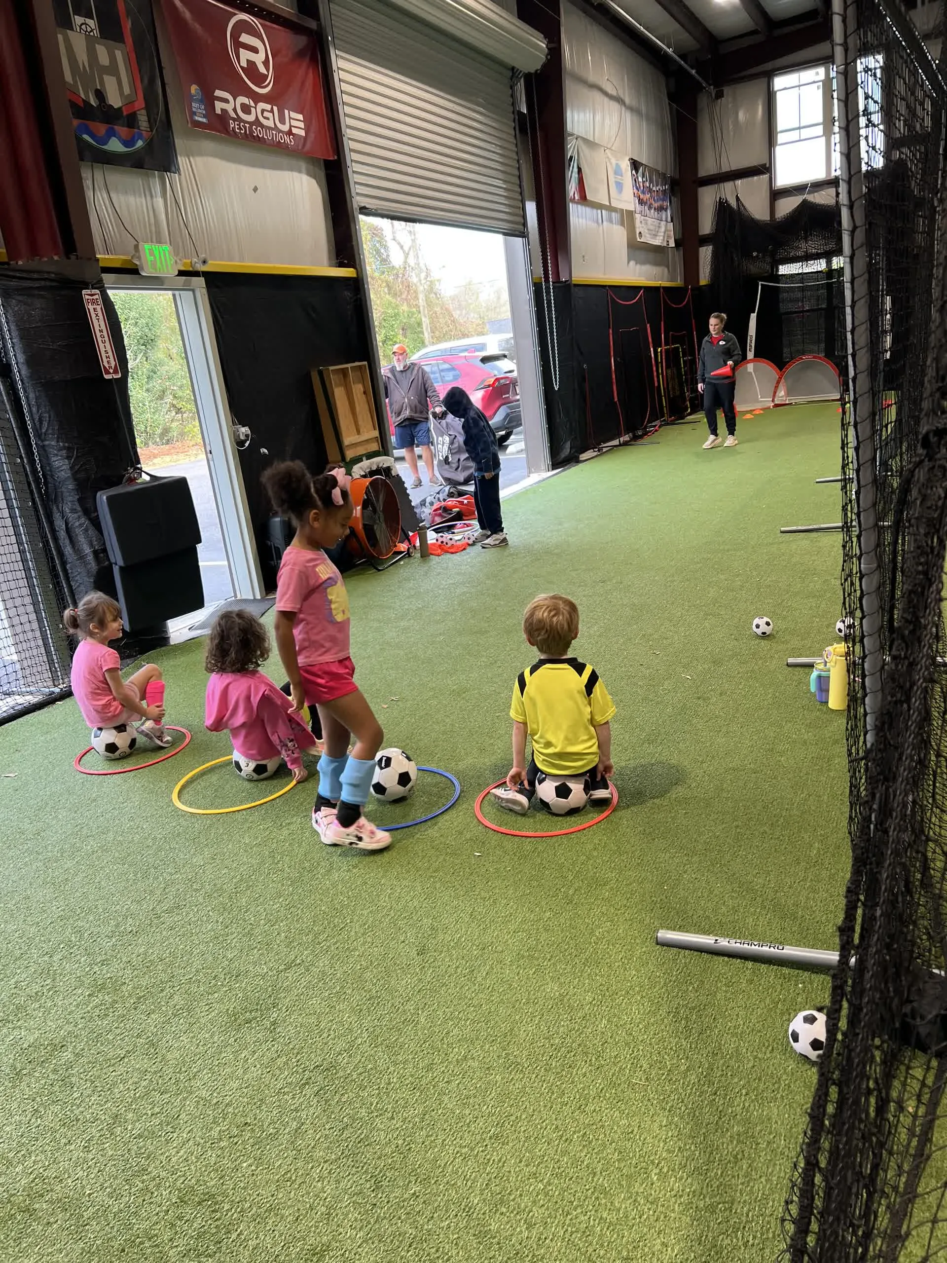 Young children standing in hula hoops with soccer balls during a toddler soccer drill